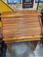 Closed roll-top secretary desk showing solid wood finish and hardware knobs.
