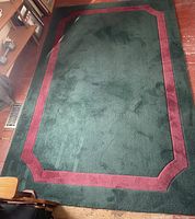 Top view of the rectangular area rug showing green center and burgundy border.