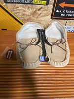 Pair of beige genuine leather slippers showing top view with lace detail and white fleece lining inside