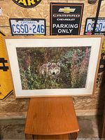 Full view of the large framed wolf photograph resting on a small wooden table, surrounded by wall decor.