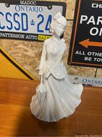 Front view of the white porcelain Paris Royal doll figurine showing the detailed dress and umbrella.