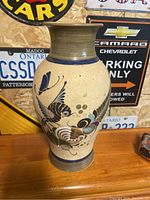 Full front view of the decorative peacock glazed pottery vase showing the painted design and shape.