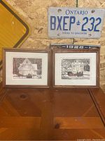 Two framed Walter Campbell prints side by side showing winter holiday scenes with horse-drawn sleighs in front of houses.