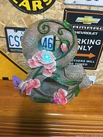 Close-up image of the solar powered patio decoration showing lit pink flower with blue light and decorative butterfly and vines.