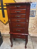 Front view of the standing jewelry box showing six drawers with metal handles, side doors closed, standing on cabriole legs.