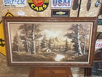 Full view of framed oil painting on canvas showing a nature landscape with cabin, trees, river, and mountains.