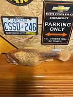 Fish carving displayed on wooden surface against wall with decorative license plates