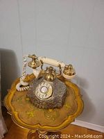 Full front view of the antique desk telephone on a decorative table, showing the whole item.
