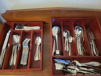 Two wooden trays holding stainless steel flatware pieces