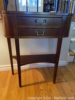 Front view showing semi-circular top, two drawers and tapered legs