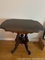 Full front view of Eastlake style occasional table showing shaped top and pedestal legs