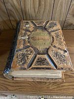 Front cover of antique family Bible showing embossed leather with floral designs and gold lettering.