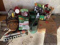 Overall view of garden supplies including sprinkler, fertilizer bags, watering can, and garden waste bags.