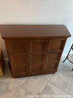 Front view of wood hall table with three paneled doors and smooth veneer tabletop.