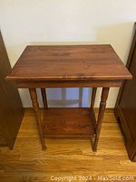 Front view of rustic maple side table showing turned legs and lower shelf