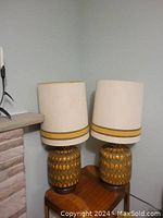 Pair of lamps on wooden side table next to fireplace, full front view