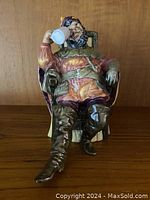 Front view of the Royal Doulton figurine showing man in medieval attire drinking from a foaming quart stein sitting in chair.