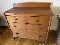 Front view of vintage pine dresser showing four drawers with round wooden knobs and a raised back edge on top surface.