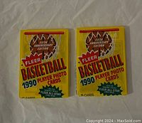 Front view of two sealed 1990 Fleer Basketball Player Photo Card packs showing the yellow packaging, branding, and basketball net graphic