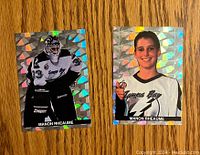 Fronts of two Manon Rheaume hockey cards with holographic foil backgrounds; one showing her in full goalie gear, the other a headshot with a thumbs up.