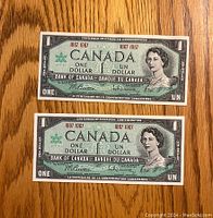 Front view of two Canadian one dollar bills from 1967 Centennial Edition side by side.