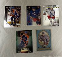 Five Wayne Gretzky hockey cards displayed front side, showcasing different team uniforms and card designs.