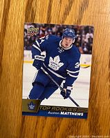 Front of the Upper Deck Auston Matthews rookie card showing player in action, Top Rookies label, and team logo.