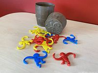 Brown barrel container with embossed monkey lid and 13 plastic monkeys in red, yellow, blue scattered around it on a wooden surface.