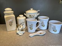 Full set of Blue Mountain Pottery kitchenware including canisters, mug, spoon rest, casserole dish, and frog brush holder with decorative decals