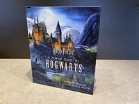 Front cover of the hardcover pop-up book showing Hogwarts Castle at night with moon and car flying on broomstick.