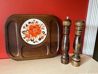 Cheeseboard tray and pair of wooden salt and pepper grinders against red wall