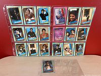 Full set of 19 Michael Jackson collector cards displayed in plastic sleeves on red background showing various images of Michael Jackson.