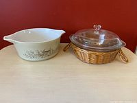 View of both Pyrex Mushroom Fancy dish and Glasbake dish with lid and wicker basket side by side.