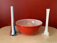 Front view of the three items showing the red bowl and two slim tall bud vases with colorful and white glass details