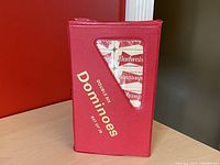 Red vinyl domino case with gold lettering showing the Budweiser branded domino tiles inside the triangular window.