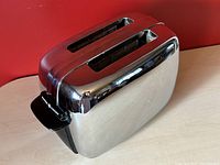 Front and top angled view of the General Electric chrome toaster showing the two wide bread slots and black lever.