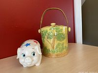 Side view of vintage Japanese ceramic cookie jar and plastic piggy bank showing details and color