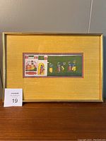 Framed artwork with gold metal frame and saffron yellow mat showing miniature Indian painting