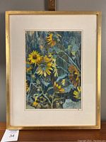 Full view of the framed sunflower artwork by Dainis Miezajs showing the wood frame and matting.