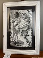 Full front view of framed pencil drawing showing white wooden frame, black mat, and Haida-style artwork under glass
