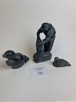 Photo showing all three Inuit soapstone carvings together on white background with MaxSold lot card