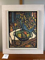 Full view of framed mid century modern style screen print art still life featuring flowers in vase and fruit on table.