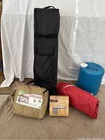 All items in the lot shown together on floor: carrying cases, red gazebo fabric, blue water jug