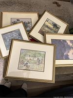 Five framed prints laid out on carpet showing various impressionist landscapes and scenes.