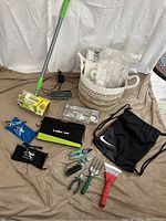 Full lot laid out including garden tools, mop, Bose speaker, sports bag, basket, solar panel, lighting kit, and glasses case.