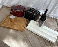 Lot overview showing all items: butcher block board, crockpot, toaster, wine cooler with bottle, and pumpkin candle.