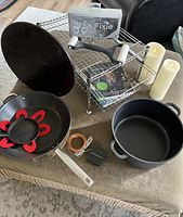 Full lot showing under cabinet organizer shelf, nonstick frying pan with silicone insert, cast iron Dutch oven, flameless LED candles, and solar string lights.
