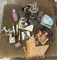 Full shot of all items included in the lot arranged on a fabric ottoman showing blender, books, water bottle, carving tools, and other accessories.