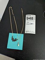 Two necklaces laid flat next to MaxSold tag labeled ‘948’