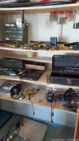 Photo showing shelves with assorted hardware, comprised of small organized parts, various hand tools, drill bits in cases, power drills, and tool boxes.